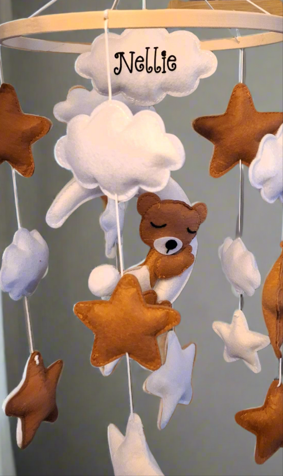 Side angle of baby cot mobile with cloud, star, and teddy bear details in focus